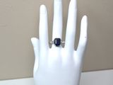 une main sur laquelle est passée une bague sertie d'une pierre bleue