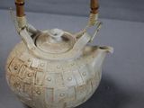 a white tea pot with a bamboo handle on a table