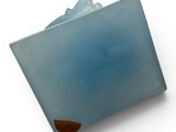 a blue glass object on a white surface with a brown edge