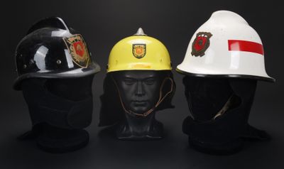 trois casques de pompier sont alignés sur un fond noir