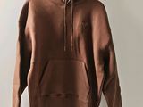 a brown hoodie hanging on a hanger in front of a white wall