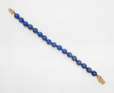 un bracelet en perles de lapis-lazuli bleu orné d'une croix en or