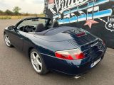 the back end of a blue sports car parked in front of a sign