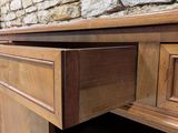 a wooden desk with a drawer on it in front of a brick wall
