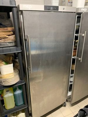 un grand réfrigérateur en acier inoxydable dans une cuisine, à côté d'une poubelle
