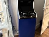 une borne d'arcade bleue et noire dans un coin de la pièce