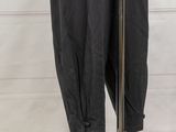 black pants hanging on a clothes rack in front of a white wall