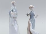 pair of porcelain figurines of a woman and a man with a dog