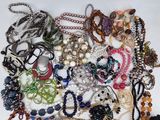 a pile of assorted necklaces and bracelets on a table