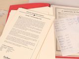 un dossier rouge avec des papiers, et d'autres papiers par-dessus