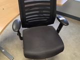 a black office chair sitting in front of a wooden desk