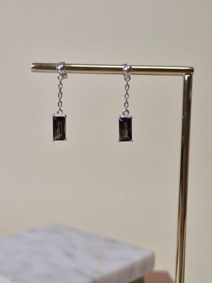 pair of black and silver square earrings on a gold plated stand