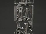 une image représentant une sculpture en métal posée sur un socle en bois, sur un fond blanc