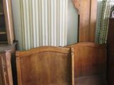 un lit avec une tête de lit en bois et une commode dans un coin
