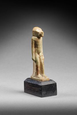 une statue égyptienne représentant un homme debout sur un socle en bois