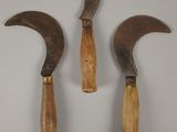 deux vieux outils à manche en bois posés l'un à côté de l'autre sur une surface blanche