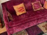 a purple couch with many pillows on it in a living room