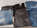 several pairs of men ' s jeans sitting on top of a white table