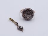 a close up of a ring and a pendant on a white surface