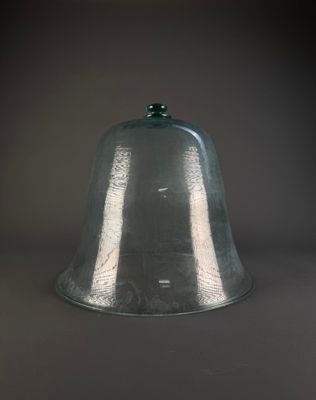 a glass bell with a green top on a table