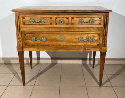 a small wooden chest of drawers on a tiled floor