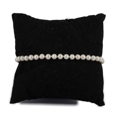 un gros plan d'un oreiller sur lequel est posé un bracelet de perles