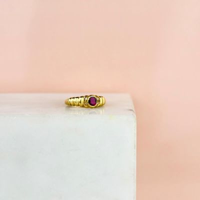 un gros plan d'une bague en or ornée d'une pierre rouge