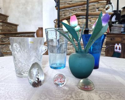 une table sur laquelle sont posés des vases et des verres, avec un mur en pierre en arrière-plan