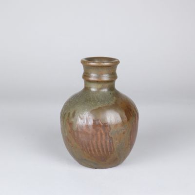 un petit vase brun posé sur une surface blanche