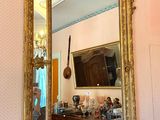 a mirror on a mantle in a room with a chandelier in the background