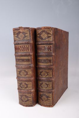 two old books sitting on top of each other on a white surface