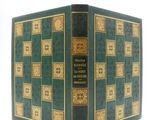un vieux livre à la couverture verte posé sur une table blanche
