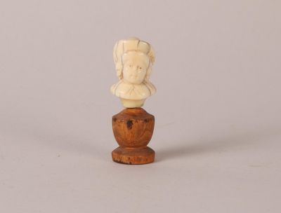 un buste antique en ivoire sculpté représentant une femme, posé sur un socle en bois