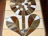 a mosaic table with a flower on it on a tiled floor