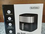 an air fryer in a box on a bed with a wooden surface