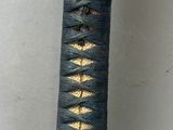 a close up of a black and gold sword with a black handle