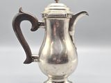 an antique silver coffee pot with a wooden handle on a white surface