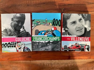 trois livres posés sur une table en bois, avec la photo d'un homme dans une voiture de course