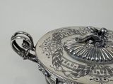 a silver plate with a lid on a white table