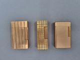 three different types of gold cigarette cases on a blue surface