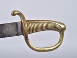 a close up of a gold colored sword with a black handle