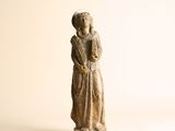 une petite statue représentant une femme debout sur une surface blanche