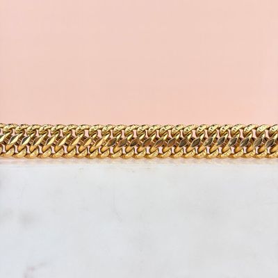 a close up of a gold chain bracelet on a pink background