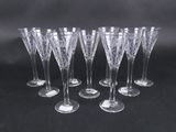 six verres à vin transparents sont alignés sur une surface noire