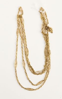 gros plan d'un collier à chaîne en or sur une surface blanche
