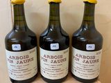three bottles of wine sit on a wooden shelf in front of a wall