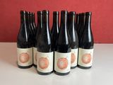 six bottles of wine sitting on top of a table next to a red wall