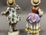 pair of porcelain figurines of a man and a woman with hats