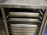 une table en acier inoxydable sur laquelle sont posés quatre bacs