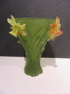 a green vase with yellow flowers in it on a table
